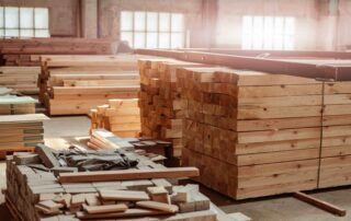 A photo of stacked industrial lumber with sun coming through windows in the background.